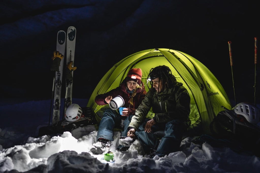 Two people winter camping making a hot drink